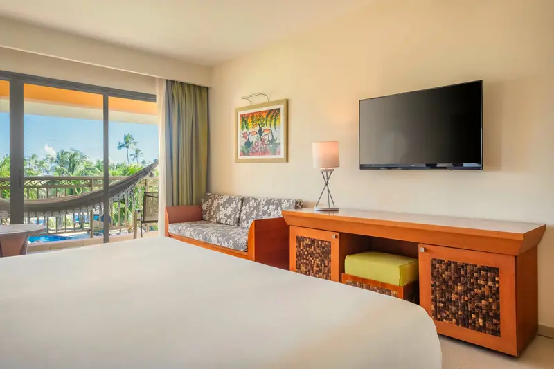 Junior suite com cama, sofá, smart TV e varanda com rede