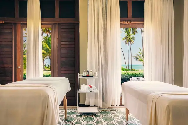 Sala de massagem para casal com duas macas e cortinas claras